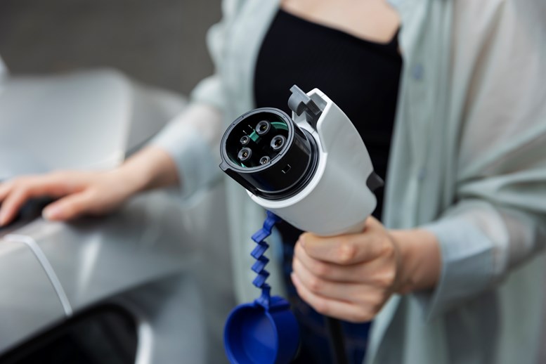 mulher com carregador de carro elétrico na mão