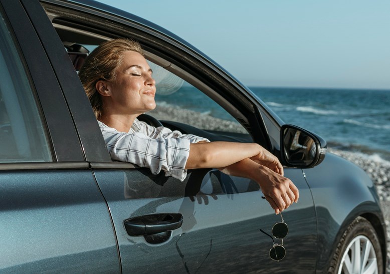 mulher dentor do carro, à beira da janela feliz por estar na praia