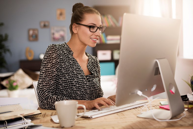 Mulher a trabalhar e a tomar notas à frente de um computador portátil