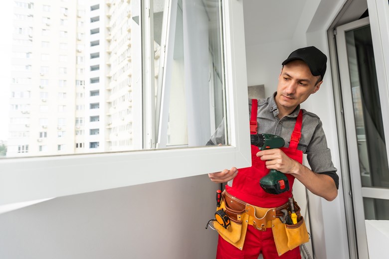 Homem instala uma janela eficiente num apartamento.