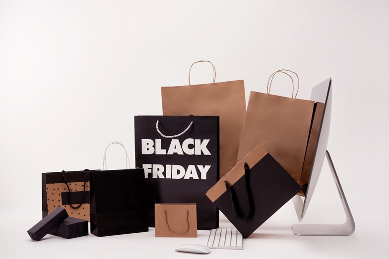 Sacos de compras alusivos à ‘Black Friday’ diante um iMac da Apple num fundo branco