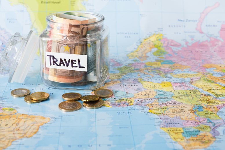 Jarro de vidro com dinheiro para fazer uma viagem em cima de um mapa do mundo.