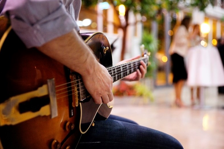 Homem de perfil a tocar guitarra num casamento.