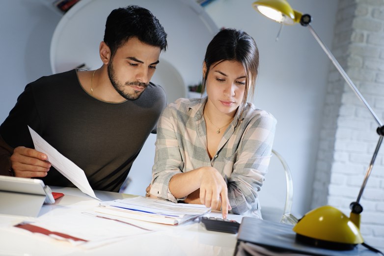 Um homem e uma mulher fazem contas às suas finanças numa mesa.