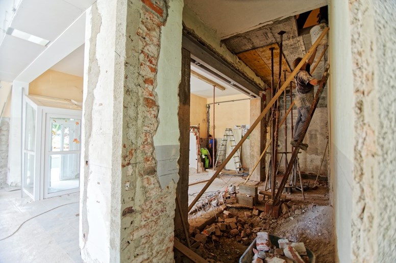 Três homens a trabalhar numa casa que está a ser remodelada.