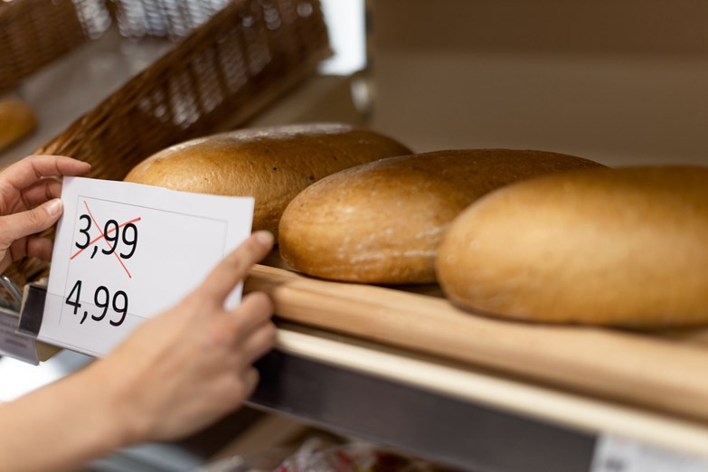 Uma pessoa analisa a etiqueta com o preço do pão.