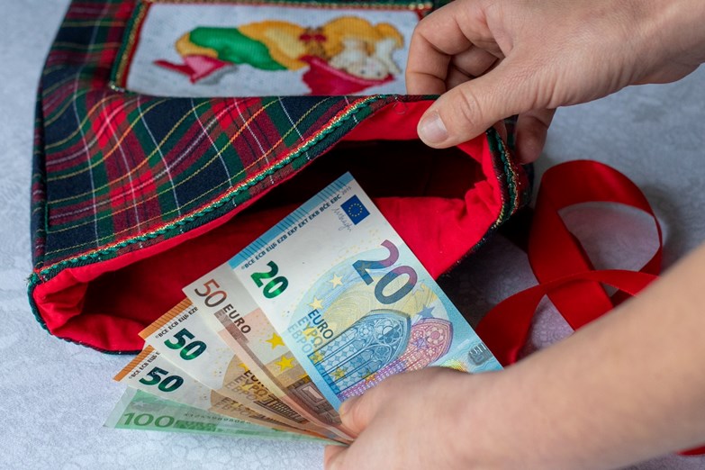 Uma pessoa coloca notas (em euros) num saco de flanela.