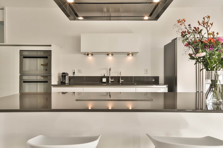 Cozinha moderna e minimalista luxuosa com ilha central, armários brancos e detalhes em preto.