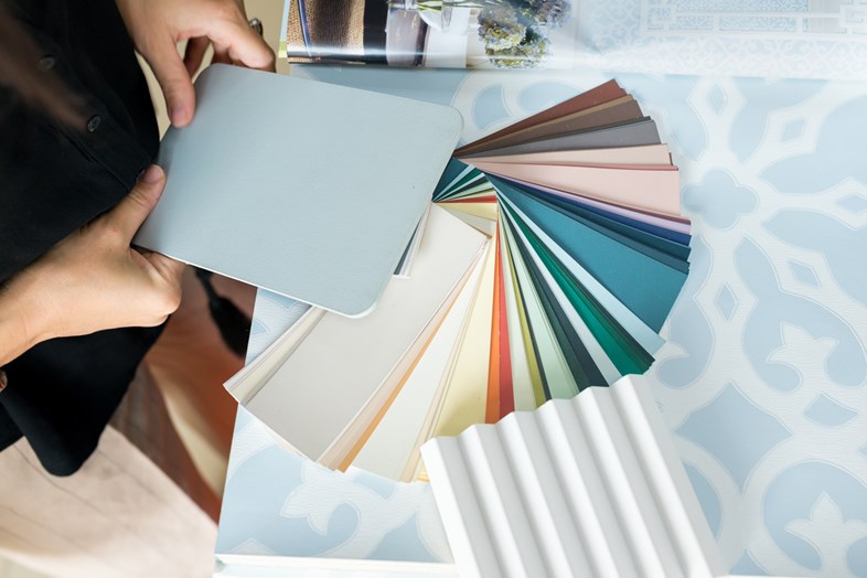 Mulher segura um livro de amostras de cores enquanto analisa diferentes tonalidades para pintar a sua cozinha.