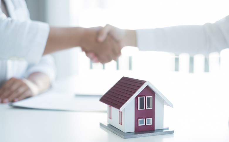 Aperto de mão entre duas pessoas celebra um acordo para a compra ou venda de uma casa.