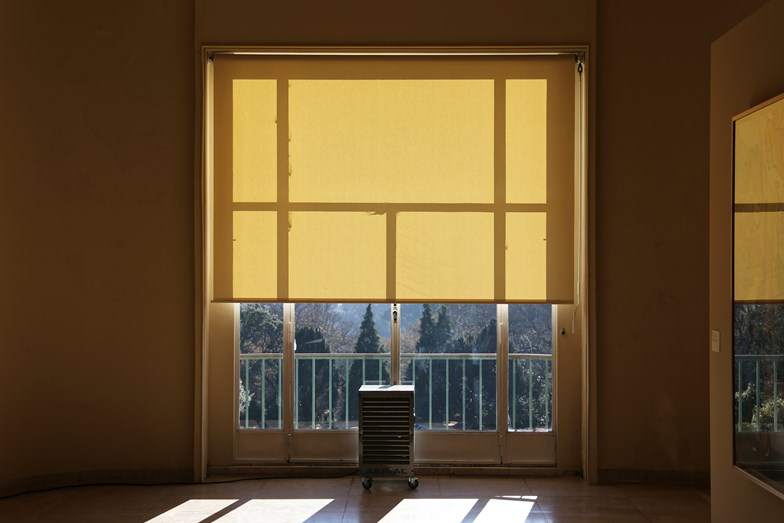 Uma grande janela tapada até meio por um estore de rolo amarelo.